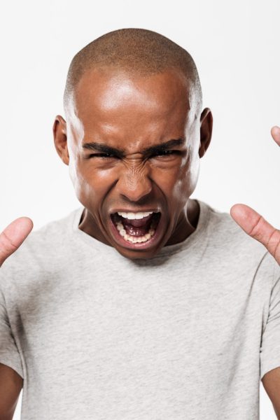 Photo of emotional screaming young african man standing isolated over white background. Looking camera.